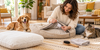 How to clean a pet bed: owner checking the care label on a removable cover with a dog and cat nearby